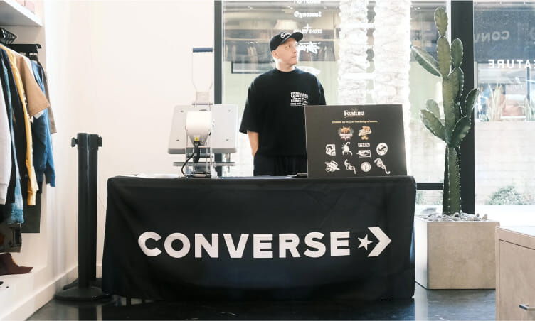 A man standing behind a table with the Converse logo