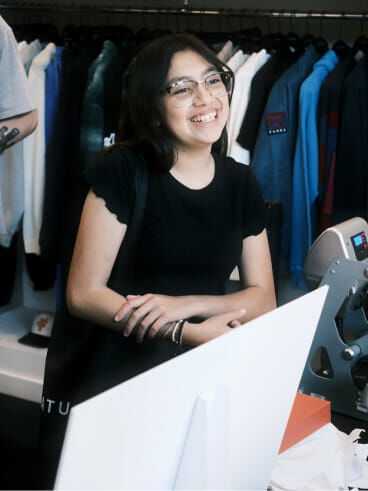 A smiling woman standing in front of a display of clothes