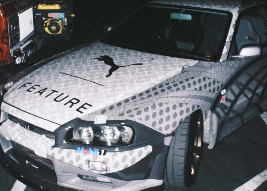 A white car customised with geometric pattern and the logos of Puma and Feature on the hood