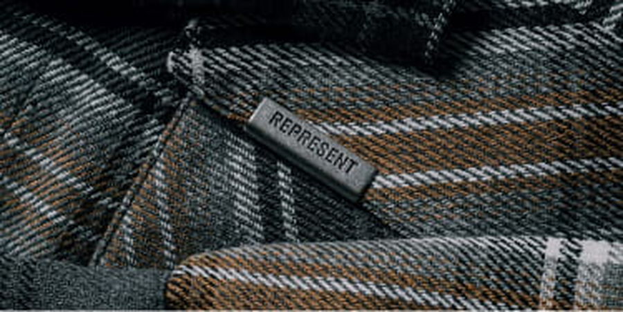 A label on a plaid fabric that says Represent